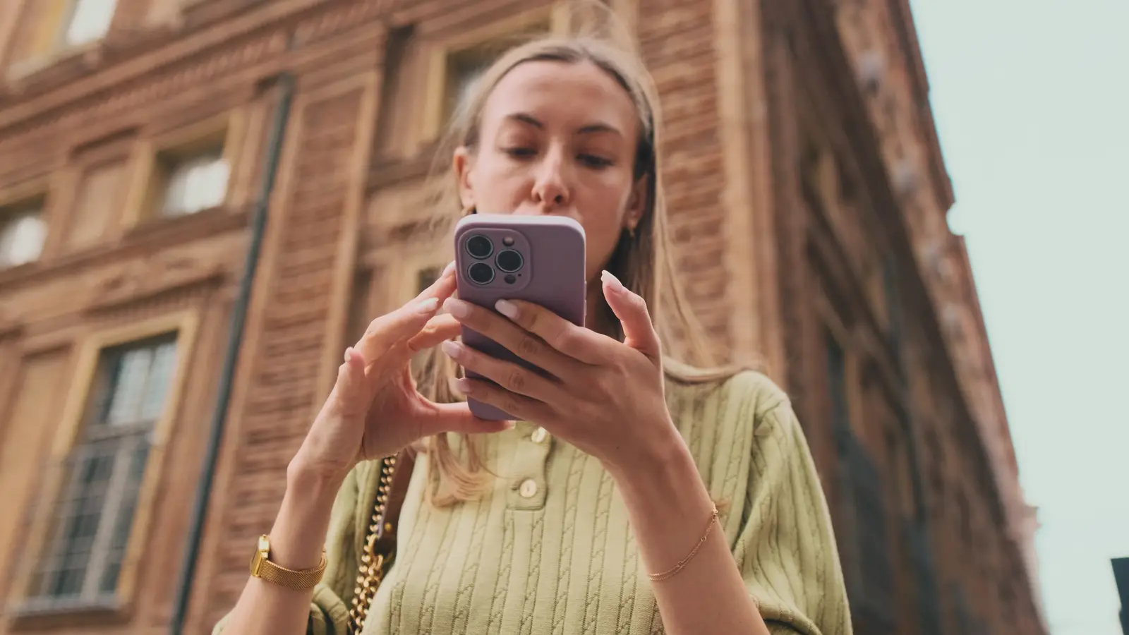 Una mujer mira su teléfono en una calle de la ciudad.