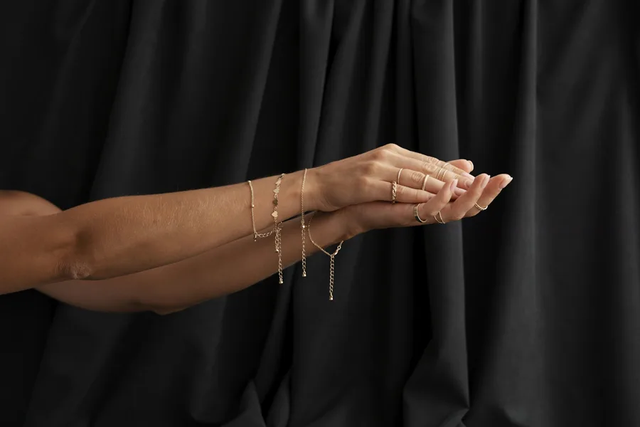 Manos con cadenas finas de oro sobre tela negra